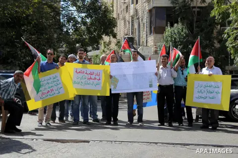 Palestinian protesters hold placards during a demonstration outside Asia corporation 'an engineering company' after being accused of cooperating with the Israeli authorities in settlement projects, in the West Bank city...
