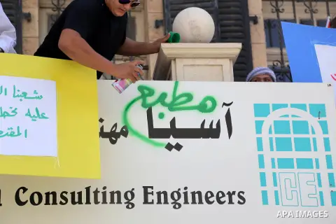 Palestinian protesters hold placards during a demonstration outside Asia corporation 'an engineering company' after being accused of cooperating with the Israeli authorities in settlement projects, in the West Bank city...