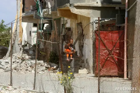 A Palestinian man holds his daughter outside his destroyed house in the town of Khan Younis in the southern Gaza Strip, Sep. 22, 2014. Gazans who endured more than 50 days of devastating Israeli bombardment are now eager...