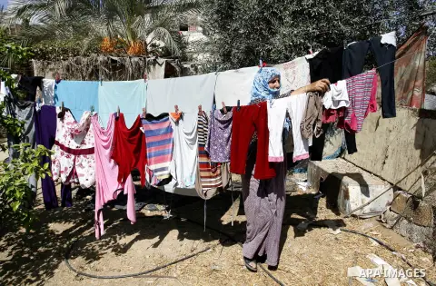 A Palestinian woman dry laundry in front of her house in the town of Khan Younis in the southern Gaza Strip, Sep. 22, 2014. Gazans who endured more than 50 days of devastating Israeli bombardment are now eager to enjoy s...