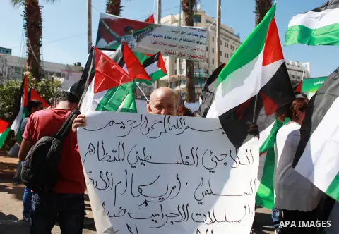 Palestinian youths hold their national flags as they celebrate annual flag-raising, in the West Bank city of Ramallah on Sep. 22, 2014. Egypt will host a brief round of indirect talks this week between Israelis and Pales...