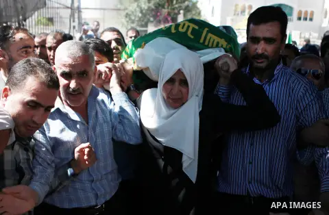 The mother of Amar Abu Aysha, a Palestinian shot dead by Israeli troops, carries her son's coffin during his funeral in the West Bank city of Hebron September 23, 2014. Israeli troops shot dead two Palestinians, includin...