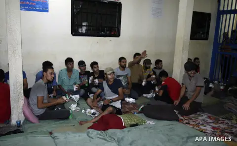 Palestinian migrants sit in a police building in Rafah after their arrival to the Palestinian side late at night in the southern Gaza strip, on September 23, 2014. Egyptian naval forces arrested would-be Palestinian immi...