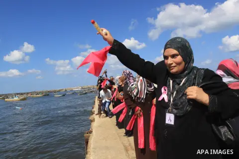Palestinian women hold banners during the Breast Cancer Awareness campaign at Gaza port in Gaza City on Oct. 01, 2014. Photo by Mohammed Asad