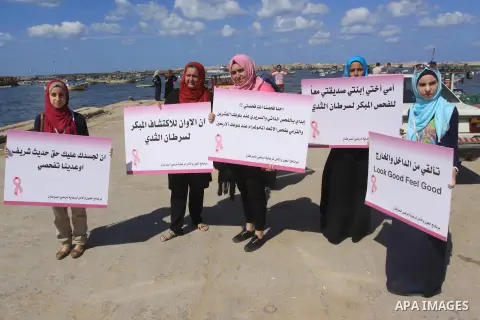 Palestinian women hold banners during the Breast Cancer Awareness campaign at Gaza port in Gaza City on Oct. 01, 2014. Photo by Mohammed Asad