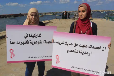 Palestinian women hold banners during the Breast Cancer Awareness campaign at Gaza port in Gaza City on Oct. 01, 2014. Photo by Mohammed Asad