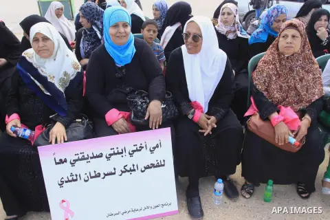 Palestinian women hold banners during the Breast Cancer Awareness campaign at Gaza port in Gaza City on Oct. 01, 2014. Photo by Mohammed Asad