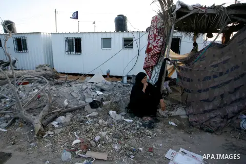 A Palestinian woman sits in front of containers donated by a charity organisation as temporary housing for whose houses were destroyed during a seven-week Israeli offensive, near the rubble of destroyed houses, in the ea...