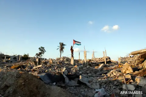Palestinian children hold their national flag on the rubble of houses which destroyed during a seven-week Israeli offensive, in the east of Khan Younis in the southern Gaza Strip October 1, 2014. An open-ended ceasefire...