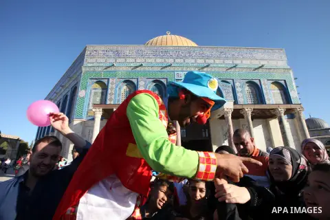 A clown plays with Palestinian children in front of the Dome of the Rock at the compound al-Aqsa mosque in Jerusalem's Old city on the first day of Eid al-Adha, October 04, 2014. Muslims around the world celebrate Eid al...