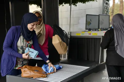 Egyptian students hold their bags at an X-ray machine after screening as they enter the Cairo University in Cairo, Egypt, October 14, 2014. Egyptian security forces surrounded the gates leading to the faculty of engineer...