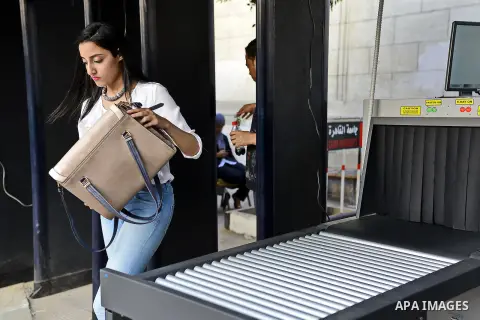 A Egyptian student holds her bag at an X-ray machine after screening as they enter the Cairo University in Cairo, Egypt, October 14, 2014. Egyptian security forces surrounded the gates leading to the faculty of engineeri...