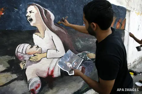 A Palestinian man paints a mural on a wall depicts a woman crying as she holds her killed husband referring to the Israeli offensive seven weeks, in Rafah in the southern Gaza Strip, October 5, 2014. Israel opened the bo...