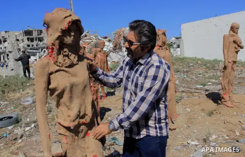 Palestinian artist Eyad Sabbah,40, stands in front of his statues standing amidst the rubble of buildings destroyed during the 50 days of conflict between Israel and Hamas last summer, in the Shejaiya neighborhood of Gaz...