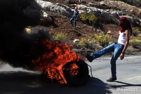 A Palestinian protester burns tires during clashes with Israeli security forces at a protest to show solidarity with al-Aqsa mosque, outside Israel's Ofer military prison near the West Bank city of Ramallah October 21, 2...
