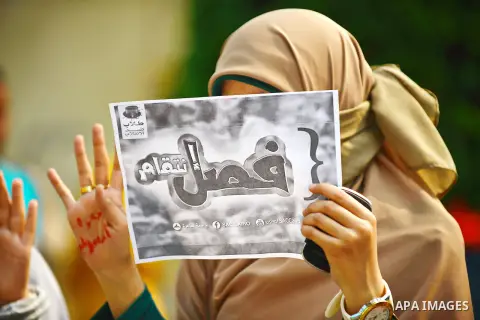 An Egyptian student who support Muslim Brotherhood and ousted president Mohammed Morsi, holds a placard and flashes Rabaa sign during a demonstration against military rule and to demand for release their fellows, at Cair...