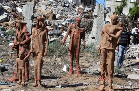 Palestinian srudents look at statues by Palestinian artist Eyad Sabbah,40, standing amidst the rubble of buildings destroyed during the 50 days of conflict between Israel and Hamas last summer, in the Shejaiya neighborho...