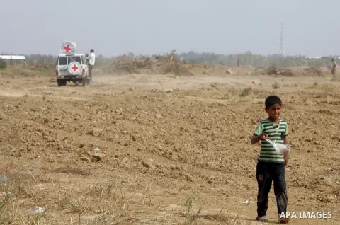 A Palestinian boy walks near an International Committee of the Red Cross (ICRC) vehicle as the comittee assists Palestinian farmers to repair their fields that were devastated during the Israeli army summer's military of...