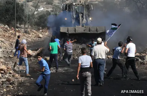 Palestinian protesters throw stones at an Israeli military bulldozer during clashes in a protest against the expropriation of Palestinian land by Israel in the West Bank village of Kfar Qaddum, near the northern city of...