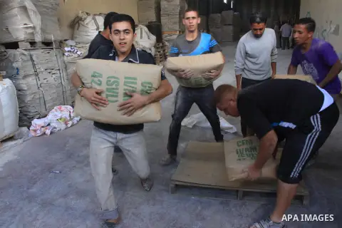 Palestinian workers carry bags of cement as Palestinians, whose houses were partially damaged by what witnesses said was Israeli shelling during the most recent conflict between Israel and Hamas, wait to receive cement o...