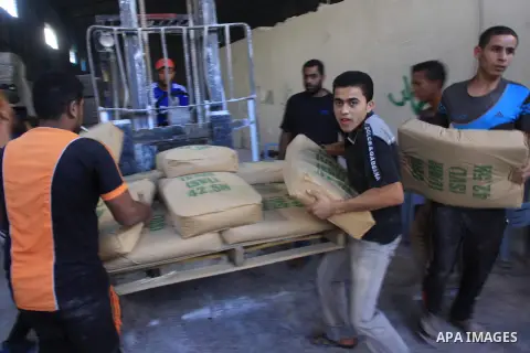 Palestinian workers carry bags of cement at center in al-Shejaiya neighbourhood in the east of Gaza City, October 30, 2014. More than 100,000 Gaza residents are still homeless. According to reports, Israel has only deliv...