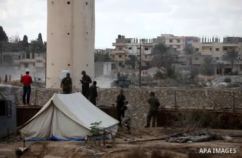 Palestinians look on as Egyptian soldiers take part in a military operation in the Egyptian city of Rafah, near the border with the southern Gaza Strip on October 30, 2014, as Egypt began setting up a buffer zone along t...