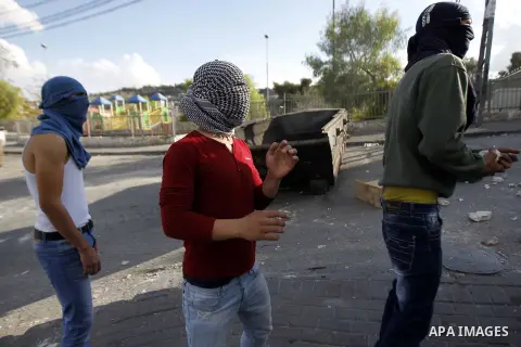 Palestinian youths take cover during clashes with Israeli security forces after Moataz Higazi was shot in east Jerusalem October 30, 2014. Israeli police shot and killed Higazi suspected of trying to kill a hard-line Jew...