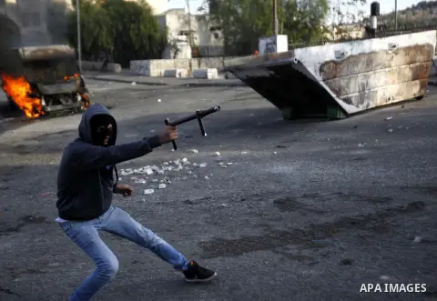 A masked Palestinian youth shoots firecrackers during clashes with Israeli security forces after Moataz Higazi was shot in east Jerusalem October 30, 2014. Israeli police shot and killed Higazi suspected of trying to kil...