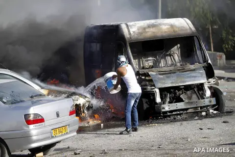 A masked Palestinian youth tries to extinguish the fire in cars during clashes with Israeli security forces after Moataz Higazi was shot in east Jerusalem October 30, 2014. Israeli police shot and killed Higazi suspected...