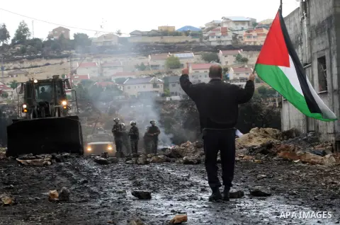A Palestinian protester waves his national flag during clashes with Israeli security forces following a weekly demonstration against the expropriation of Palestinian land by Israel in the village of Kafr Qaddum, near Nab...