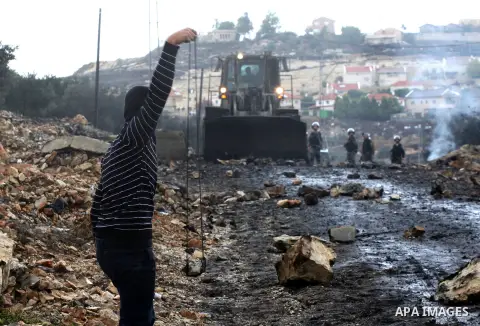 A Palestinian protester prepares to hurl a stone towards Israeli security forces during clashes following a weekly demonstration against the expropriation of Palestinian land by Israel in the village of Kafr Qaddum, near...