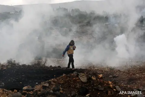 A Palestinian protester take cover from tear gas fired by Israeli security forces during clashes following a weekly demonstration against the expropriation of Palestinian land by Israel in the village of Kafr Qaddum, nea...