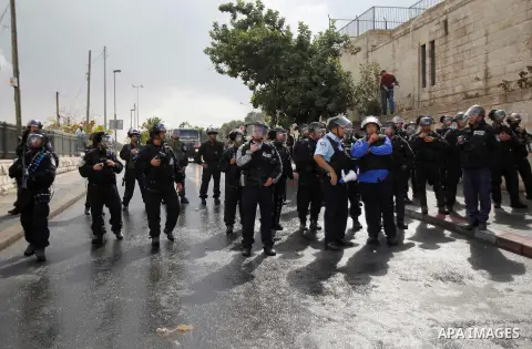 Israeli security forces stand guard as Palestinian Muslim worshippers (unseen) perform traditional Friday prayers on a street outside the Old City in east Jerusalem on October 31, 2014, following restrictions by Israeli...