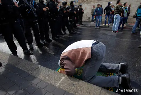 Israeli security forces stand guard as Palestinian Muslim worshippers perform traditional Friday prayers on a street outside the Old City in east Jerusalem on October 31, 2014, following restrictions by Israeli police to...