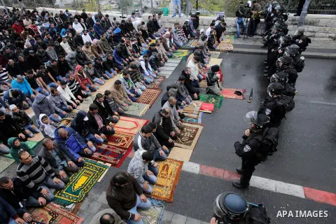 Israeli security forces stand guard as Palestinian Muslim worshippers perform traditional Friday prayers on a street outside the Old City in east Jerusalem on October 31, 2014, following restrictions by Israeli police to...