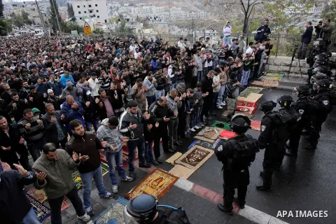 Israeli security forces stand guard as Palestinian Muslim worshippers perform traditional Friday prayers on a street outside the Old City in east Jerusalem on October 31, 2014, following restrictions by Israeli police to...