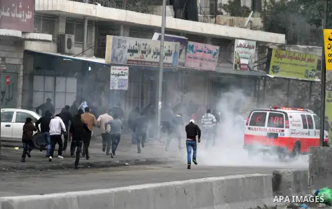 Palestinian demonstrators run for cover from tear gas fired by Israeli security forces during clashes at the Qalandia checkpoint between Ramallah and Jerusalem City following a rally by supporters of the Hamas movement a...