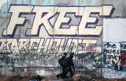 Israeli security forces walk in front of Israel's controversial separation-barrier during clashes with Palestinian demonstrators at the Israeli Qalandia checkpoint between the West Back city of Ramallah and Jerusalem on...