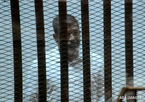 Egypt's deposed Islamist president Mohamed Morsi gestures inside the defendant's cage during his trial in Cairo on Nov. 01, 2014. Morsi is being tried at a courtroom in the Police Academy in New Cairo along with 14 other...