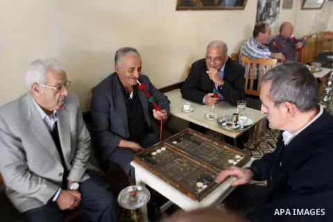 An elderly Palestinian men play backgammon and smoke flavoured tobacco water pipes or 'shisha' at a cafe in the West Bank city of Nablus on Nov. 02, 2014. Photo by Nedal Eshtayah