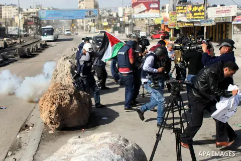 Palestinian journalists and media members run for cover from tear gas fired by Israeli security forces during clashes with Palestinian protester at the Qalandia checkpoint between Ramallah and Jerusalem City following a...