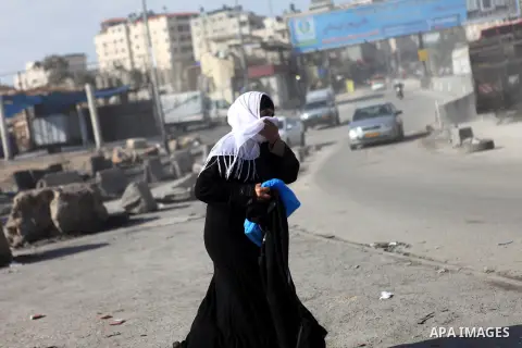 A Palestinian woman covers her face from tear gas fired by Israeli security forces during clashes with Palestinian protester at the Qalandia checkpoint between Ramallah and Jerusalem City following a rally against the re...