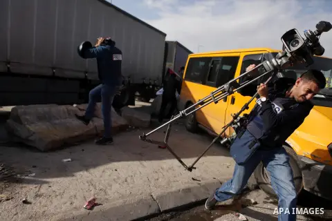 Palestinian journalists and media members run for cover from tear gas fired by Israeli security forces during clashes with Palestinian protester at the Qalandia checkpoint between Ramallah and Jerusalem City following a...