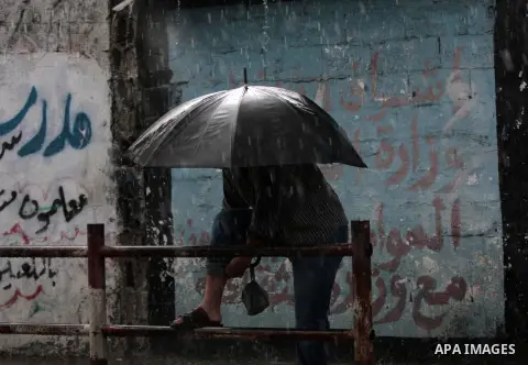 A Palestinian man holds an umbrella, on a rainy day in the east of Gaza City November 3, 2014. Photo by Yasser Qudih