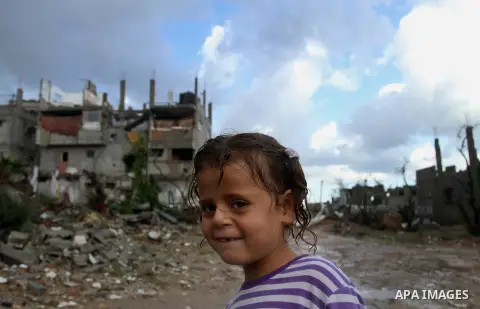 A Palestinian girl looks on as she stands in front of the ruins of a house that witnesses said was destroyed by Israeli shelling during the most recent conflict between Israel and Hamas, on a rainy day in the east of Gaz...