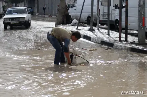 A Palestinian boy tries to remove a water in a street, on a rainy day in the east of Gaza City November 3, 2014. . Photo by Yasser Qudih