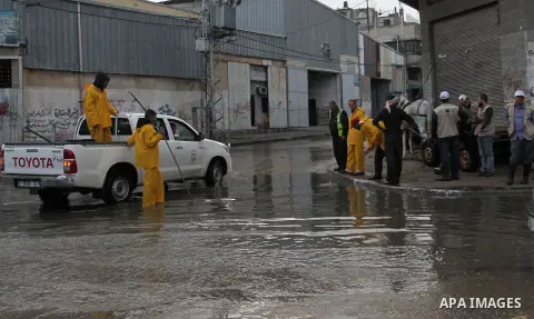 Palestinian civil defence try to remove a water in a street, on a rainy day in the east of Gaza City November 3, 2014. . Photo by Yasser Qudih