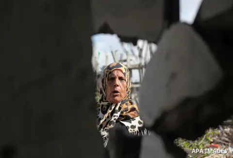 A Palestinian woman gestures as she stands near the ruins of a house that witnesses said was destroyed by Israeli shelling during the most recent conflict between Israel and Hamas, on a rainy day in the east of Gaza City...