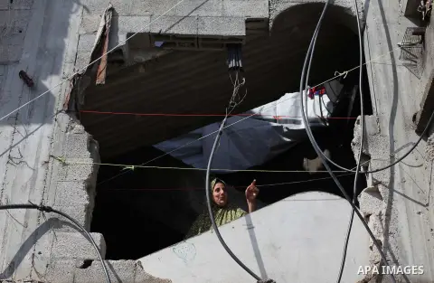 Palestinians look out the window of their house that witnesses said was damaged by Israeli shelling during the most recent conflict between Israel and Hamas, on a rainy day in the east of Gaza City November 3, 2014. Phot...