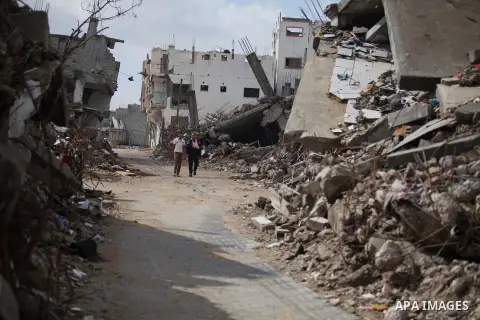 Palestinians walk past the ruins of a house that witnesses said was destroyed by Israeli shelling during the most recent conflict between Israel and Hamas, on a rainy day in the east of Gaza City November 3, 2014. Photo...